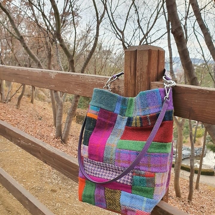 보라색 손잡이와 가죽 바닥의 울 가방